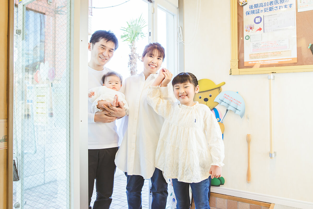 ホワイト歯科クリニックの入り口にいる親子4人の家族写真